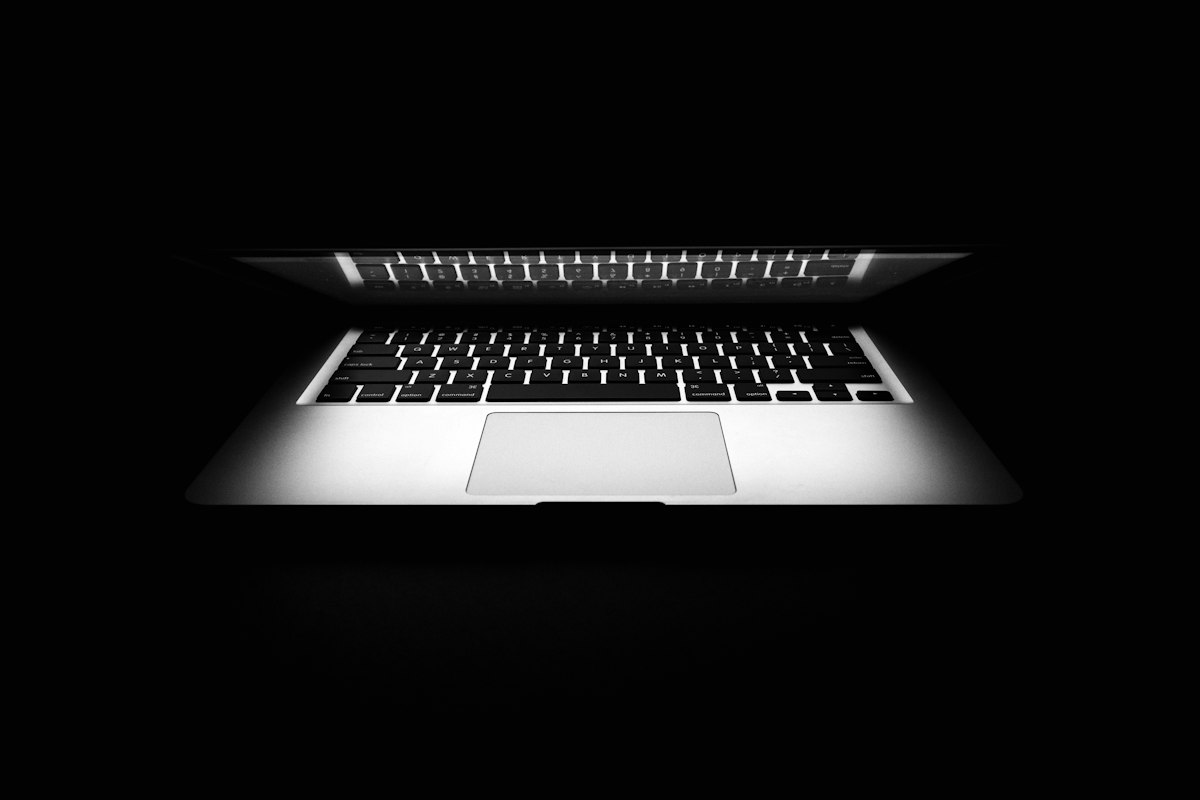 Un portátil abierto sobre fondo oscuro, con la pantalla apagada